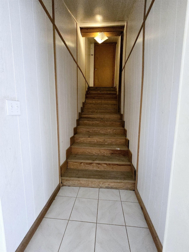 stairs with tile patterned floors and wooden walls