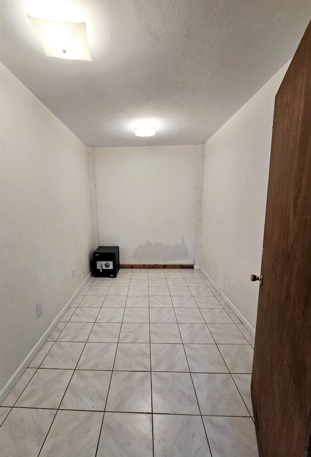 spare room featuring light tile patterned flooring and baseboards