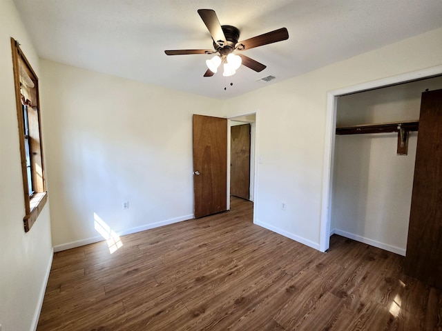 unfurnished bedroom featuring dark wood-type flooring, visible vents, baseboards, and a closet