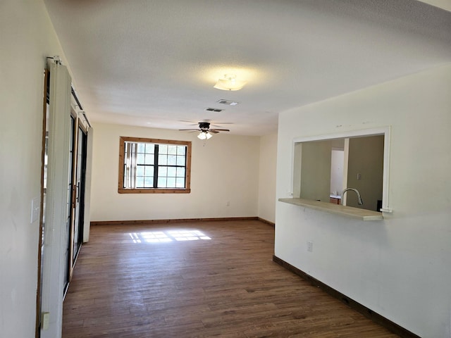 spare room featuring baseboards, wood finished floors, visible vents, and ceiling fan