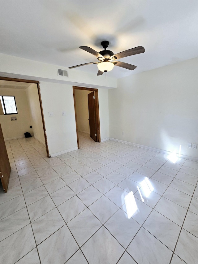 unfurnished room with light tile patterned flooring, visible vents, baseboards, and a ceiling fan