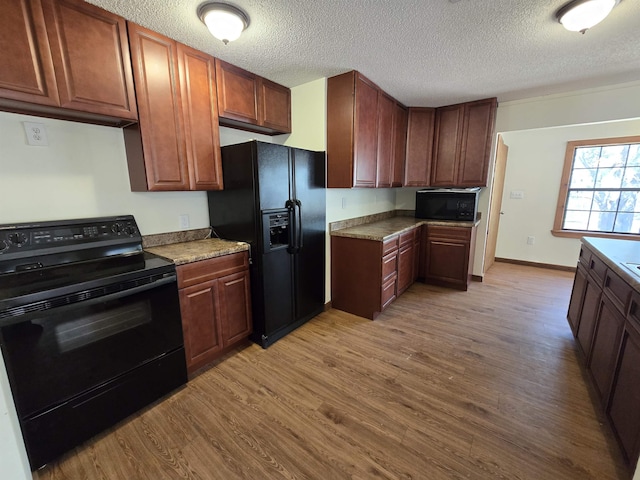 kitchen featuring black appliances, wood finished floors, baseboards, and a textured ceiling