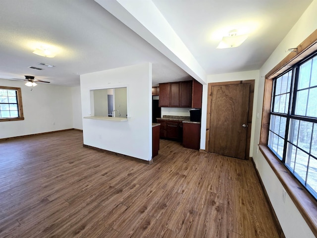 kitchen with black refrigerator, baseboards, dark wood finished floors, dark brown cabinetry, and light countertops