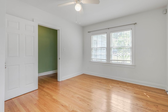 spare room featuring light wood-style floors, a ceiling fan, and baseboards