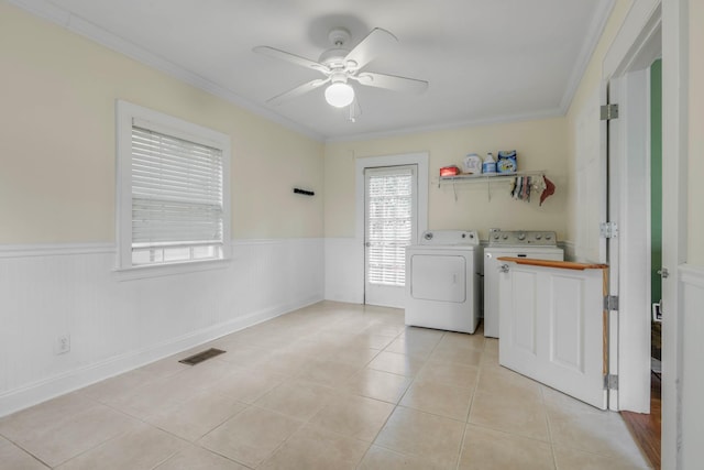 clothes washing area featuring laundry area, crown molding, washer and clothes dryer, a wainscoted wall, and a ceiling fan