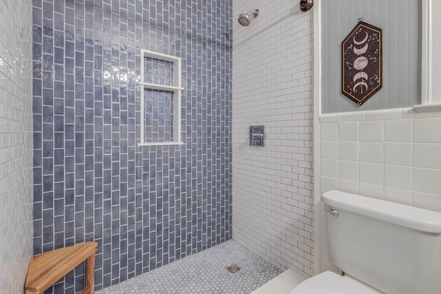 bathroom featuring tile walls, toilet, and tiled shower