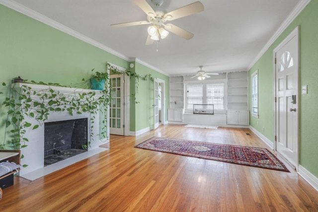 unfurnished living room featuring built in features, wood finished floors, baseboards, ceiling fan, and a tile fireplace