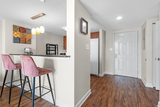 300 S Duval St Unit 503, Tallahassee, FL 32301 - kitchen with freestanding refrigerator, dark wood-style floors, a kitchen breakfast bar, baseboards, and dark countertops