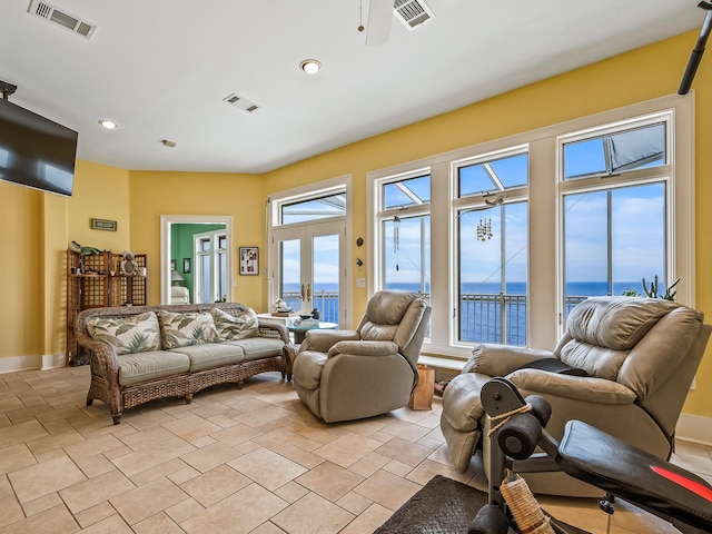 tiled living room featuring french doors, a water view, and ceiling fan