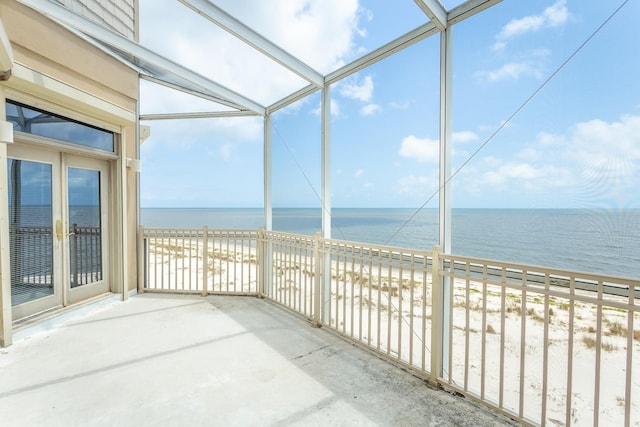 unfurnished sunroom featuring a beach view, a water view, and a healthy amount of sunlight