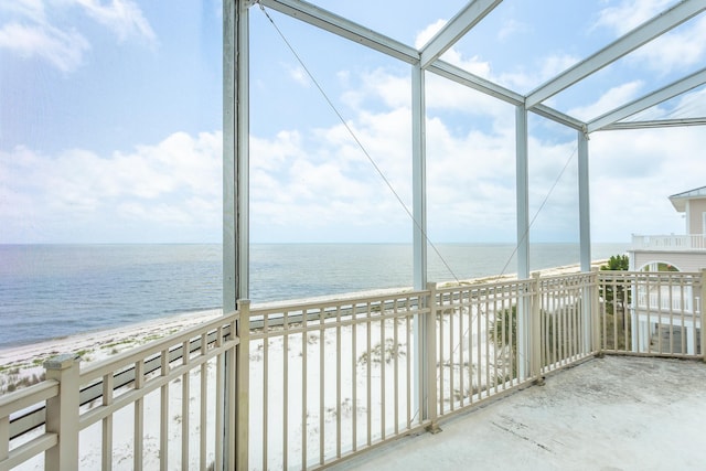 unfurnished sunroom with a water view, a healthy amount of sunlight, and a beach view