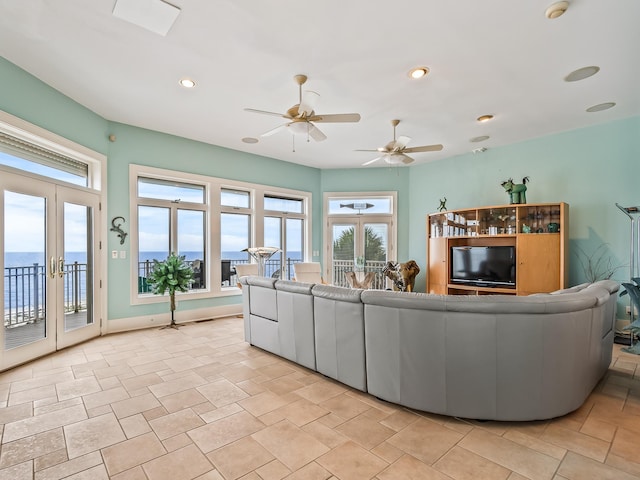 living room featuring ceiling fan, a water view, and french doors