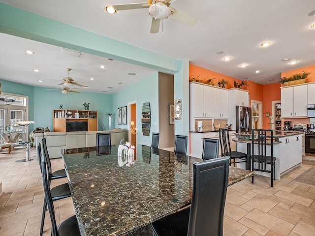 kitchen featuring a breakfast bar, white cabinets, a spacious island, ceiling fan, and stainless steel appliances