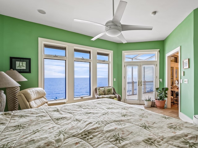 bedroom with access to exterior, ceiling fan, a water view, and multiple windows