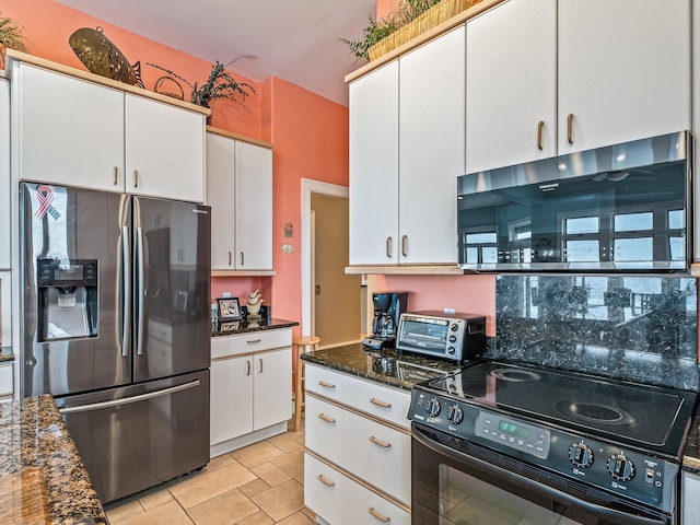 kitchen with white cabinets, appliances with stainless steel finishes, dark stone counters, and light tile patterned flooring