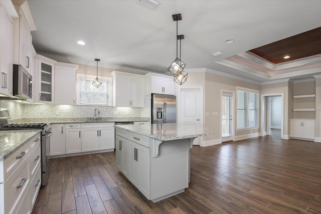 kitchen featuring decorative light fixtures, a center island, stainless steel appliances, and white cabinetry