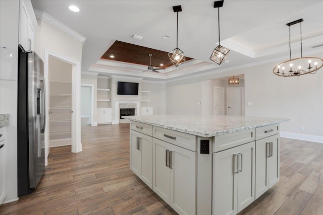 kitchen featuring a tray ceiling, stainless steel fridge with ice dispenser, a center island, and white cabinetry