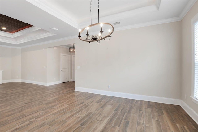 empty room with hardwood / wood-style floors, a chandelier, crown molding, and a tray ceiling