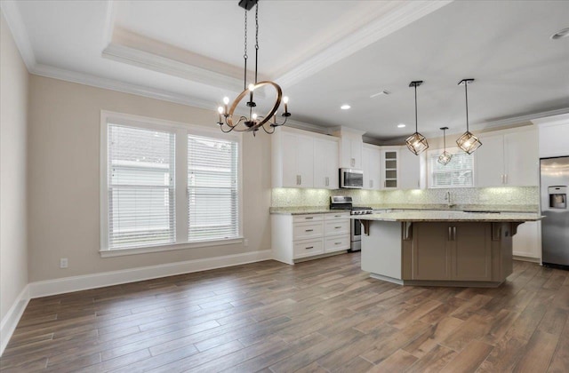 kitchen with hanging light fixtures, light stone counters, a breakfast bar, white cabinets, and appliances with stainless steel finishes