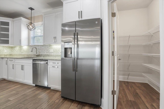 kitchen with appliances with stainless steel finishes, light stone counters, sink, decorative light fixtures, and white cabinetry