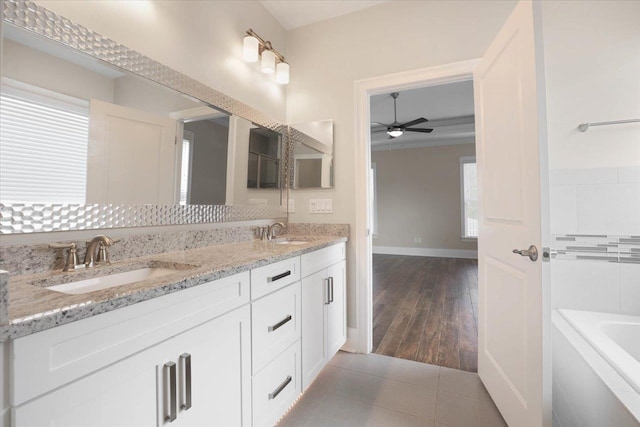 bathroom featuring tile patterned flooring, vanity, ceiling fan, and tiled tub