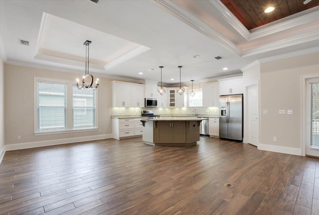 kitchen featuring stainless steel appliances, a kitchen island, decorative light fixtures, white cabinets, and ornamental molding