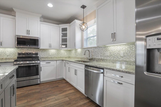 kitchen featuring white cabinetry, sink, dark wood-type flooring, hanging light fixtures, and stainless steel appliances