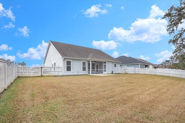 rear view of house featuring a yard and a sunroom