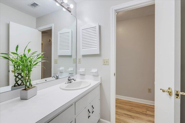 bathroom featuring vanity, baseboards, wood finished floors, and visible vents