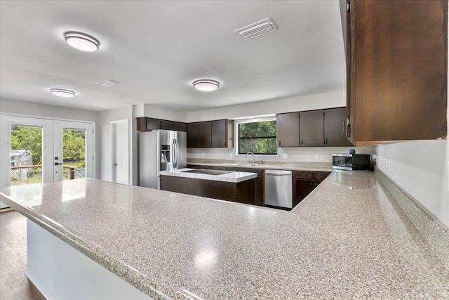 16552 198th Trace, Trace, FL 32071 - kitchen with appliances with stainless steel finishes, french doors, light countertops, dark brown cabinetry, and a peninsula