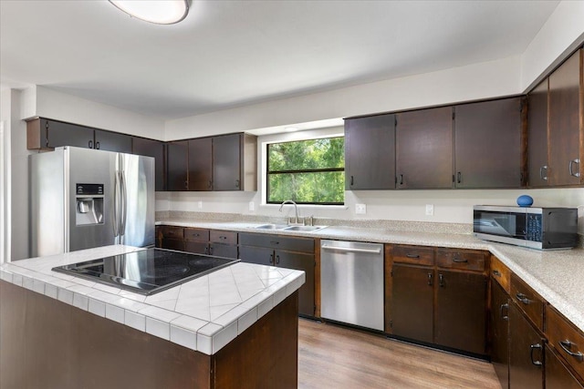 16552 198th Trace, Trace, FL 32071 - kitchen featuring appliances with stainless steel finishes, dark brown cabinets, light wood finished floors, and tile countertops