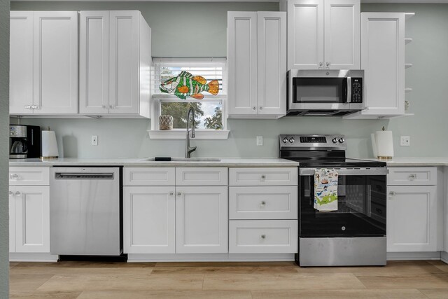 131 Delaware St, Carrabelle, FL 32323 - kitchen with stainless steel appliances, white cabinets, light countertops, and light wood-style flooring