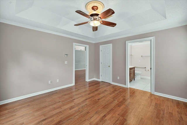 2032 Ascot Way, Tallahassee, FL 32312 - unfurnished bedroom featuring a raised ceiling, light wood-style floors, ornamental molding, ensuite bath, and ceiling fan
