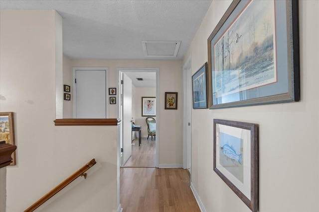 hall with light hardwood / wood-style flooring and a textured ceiling