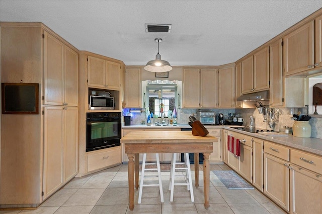 kitchen with pendant lighting, black oven, tasteful backsplash, and light tile patterned flooring