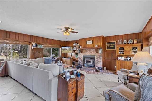 tiled living room featuring a textured ceiling, ceiling fan, and wood walls