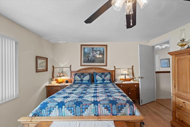 bedroom with ceiling fan, light hardwood / wood-style floors, and a textured ceiling