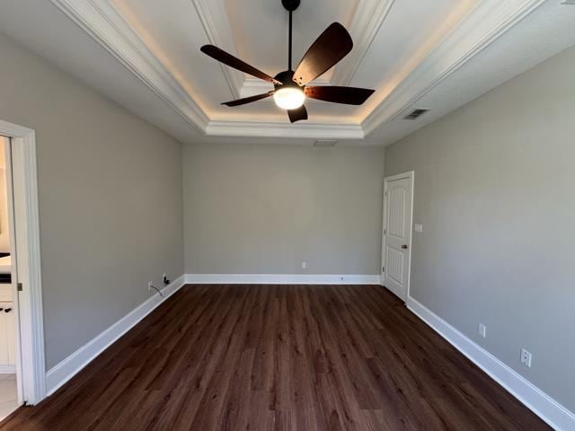 spare room featuring a tray ceiling, ceiling fan, dark hardwood / wood-style floors, and ornamental molding