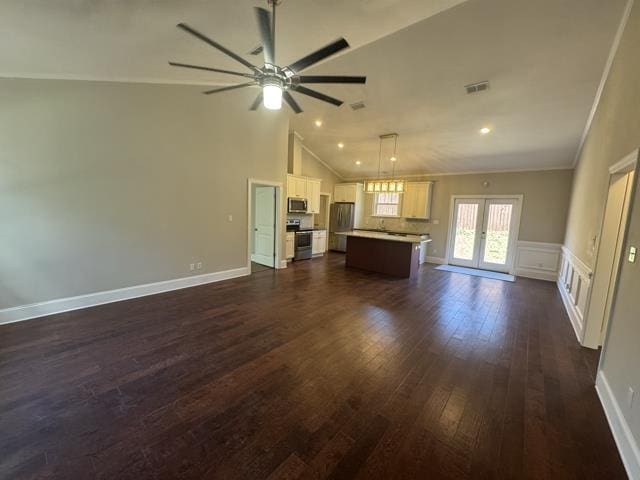 unfurnished living room with french doors, crown molding, vaulted ceiling, dark hardwood / wood-style floors, and ceiling fan