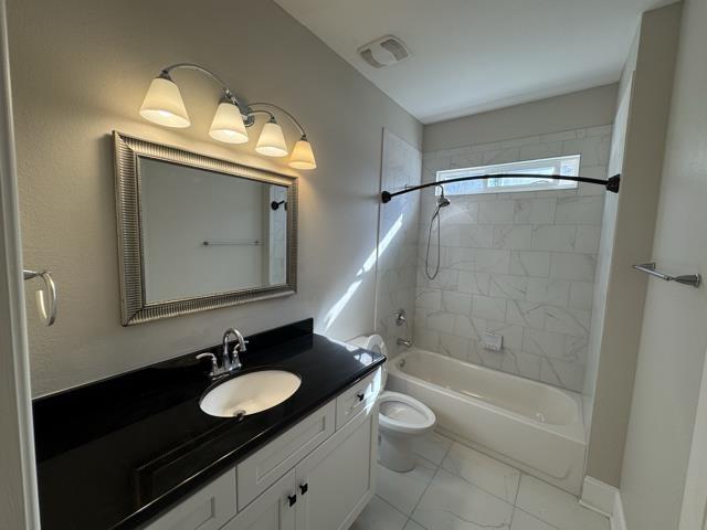 full bathroom with vanity, tiled shower / bath combo, and toilet