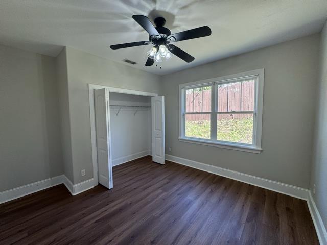 unfurnished bedroom featuring dark hardwood / wood-style flooring, a closet, and ceiling fan