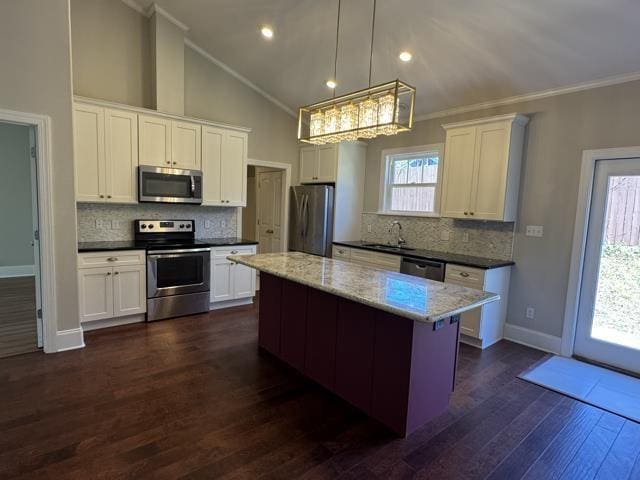 kitchen featuring dark wood-type flooring, stainless steel appliances, a kitchen island, pendant lighting, and white cabinets