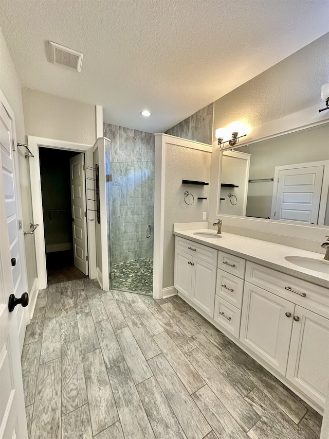 3646 Homestead Rd, Tallahassee, FL 32309 - full bathroom featuring a shower stall, a textured ceiling, wood finished floors, double vanity, and recessed lighting