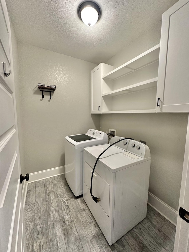 3646 Homestead Rd, Tallahassee, FL 32309 - clothes washing area with cabinet space, light wood-style floors, a textured ceiling, separate washer and dryer, and baseboards