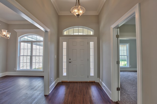 entrance foyer with ornamental molding, dark wood-style flooring, baseboards, and an inviting chandelier