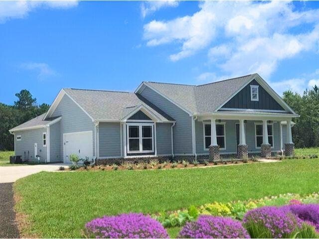 craftsman inspired home with a porch, an attached garage, driveway, and a front lawn