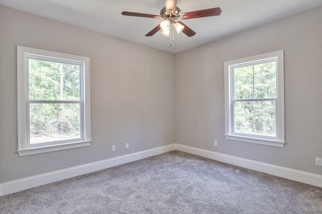 carpeted empty room with plenty of natural light, a ceiling fan, and baseboards