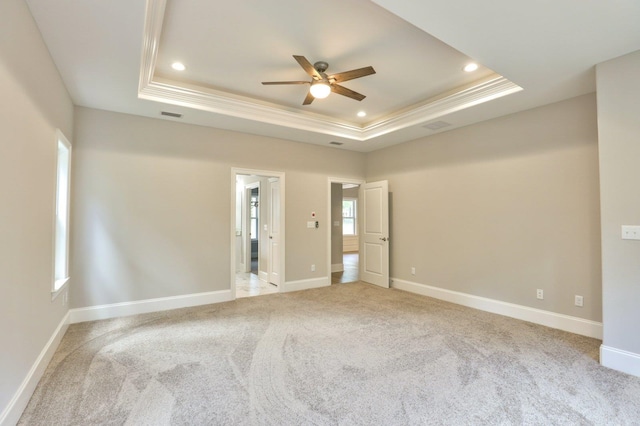 empty room with light carpet, baseboards, and a raised ceiling