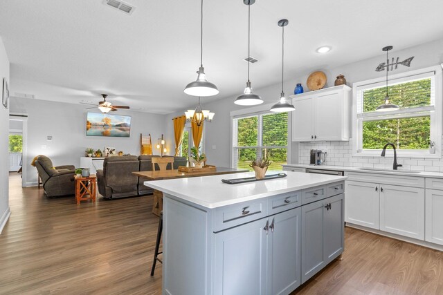 kitchen featuring decorative light fixtures, sink, a center island, and wood-type flooring