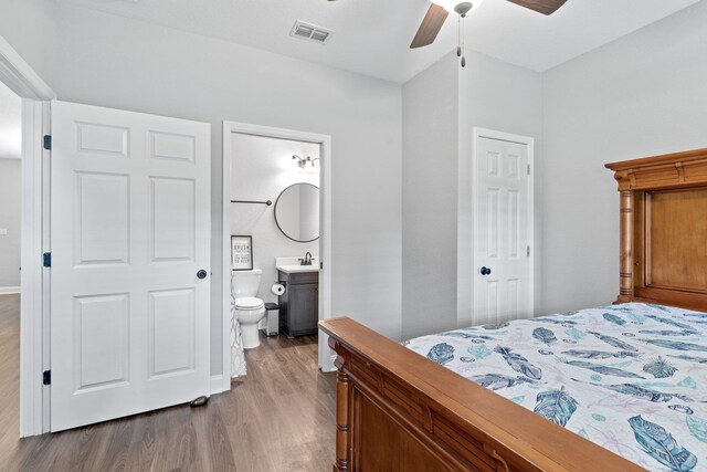 bedroom with ensuite bathroom, light hardwood / wood-style flooring, ceiling fan, and sink